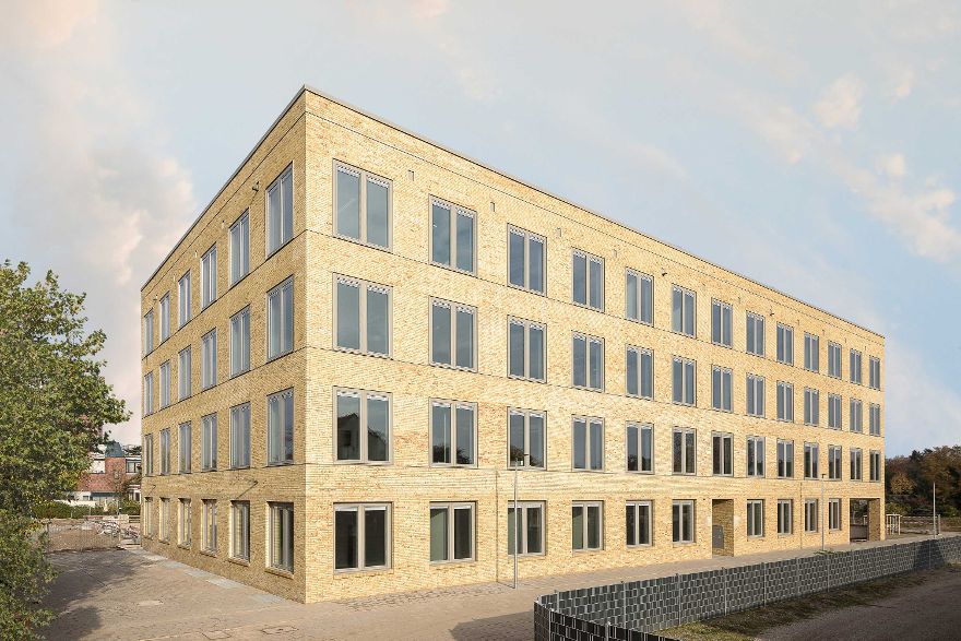 Ein dreistöckiges rechteckiges Bürogebäude mit gelb-orangenem Mauerwerk